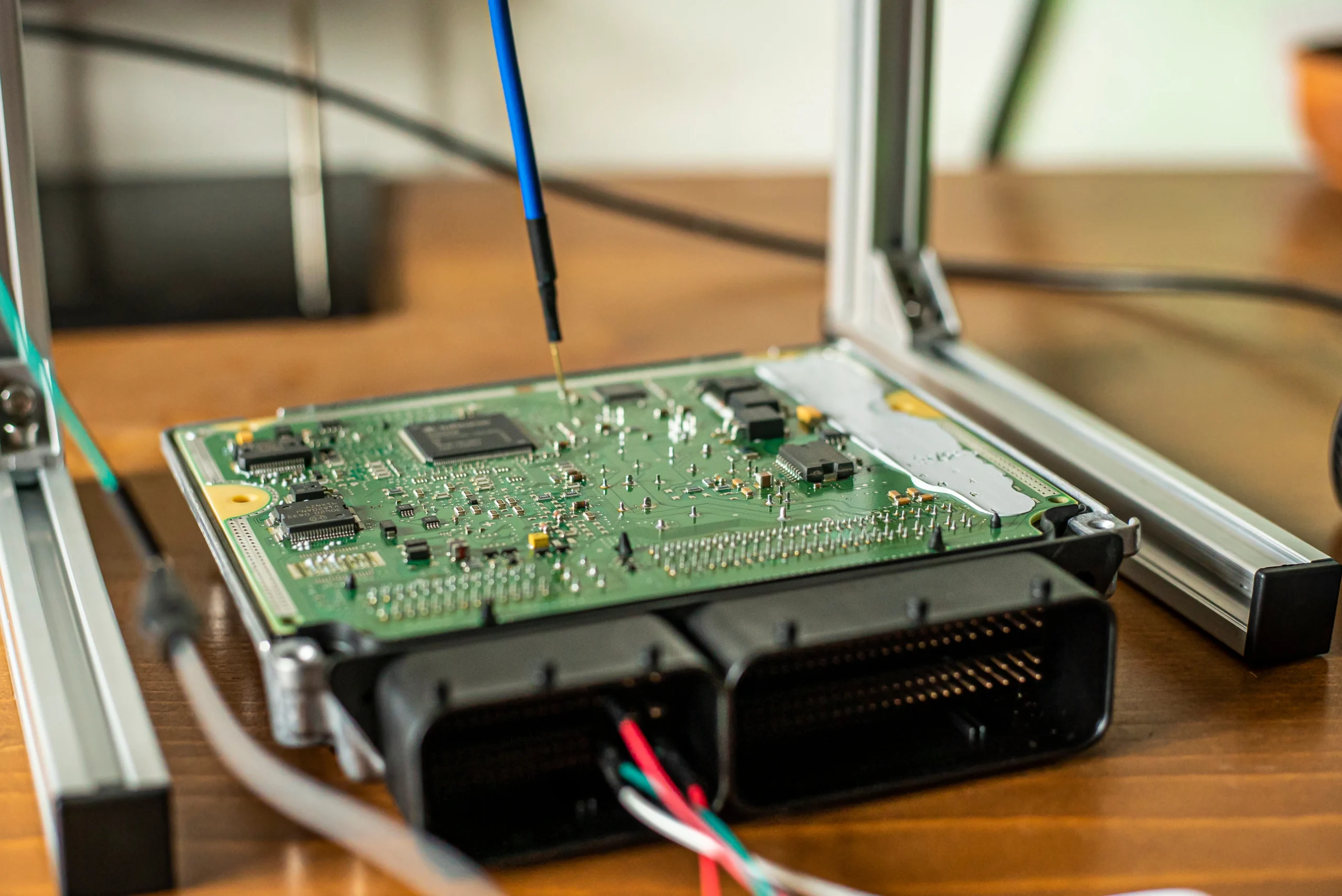 Automotive ECU circuit board connected to specialist electronic testing and programming equipment